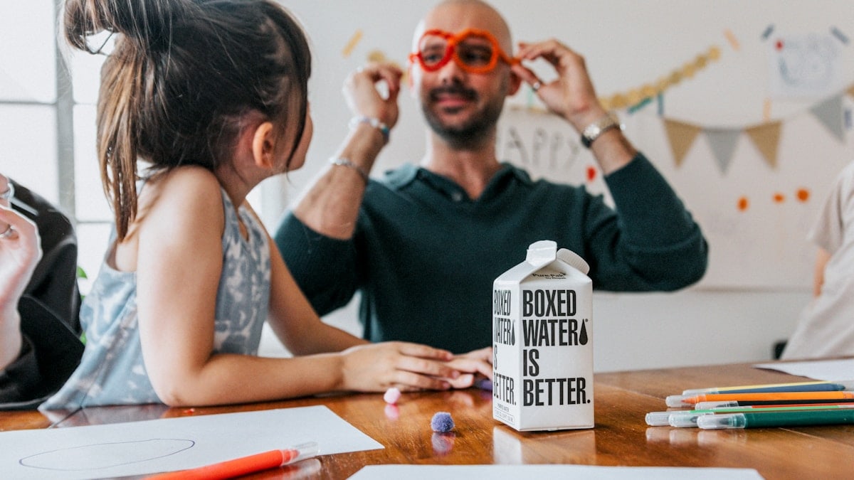 a man and a little girl sitting at a table with a milk carton